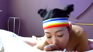Молодая азиатка с повязкой и собранными волосами сосет белому партнеру с камерой