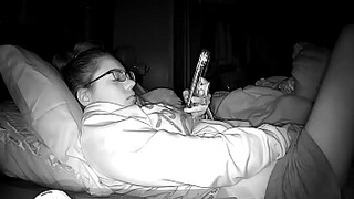 Очкастая девица в шортах и свитере мастурбирует пальцами на кровати перед сном