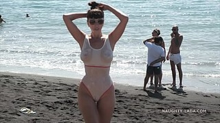 Русская дама с натуральными дойками и в белом купальнике позирует на общественном пляже