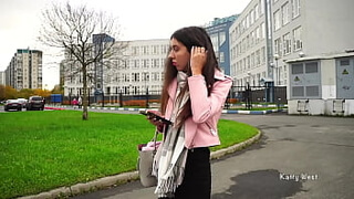 Молодая россиянка в розовой куртке и с шарфом на шее склонилась над ухажером и взяла в рот его конец